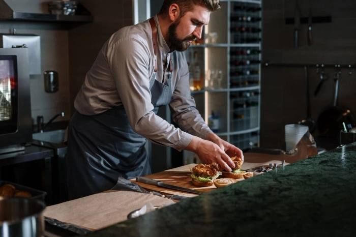 Proffesjonell baker som jobber i bakeri og lager en hamburger